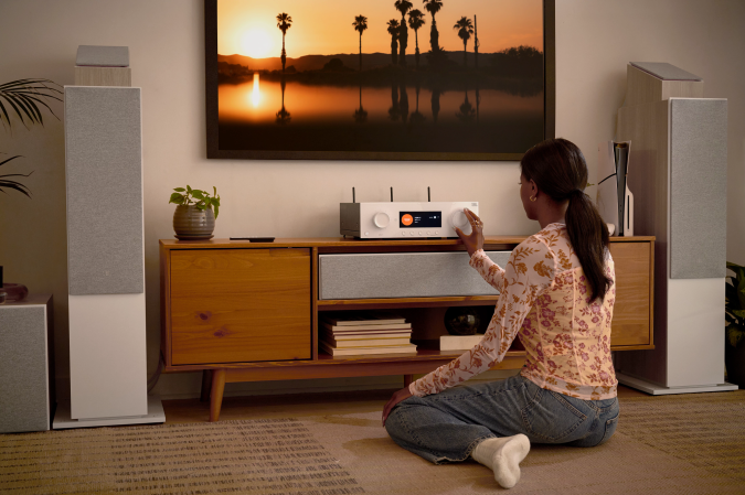 Latte-colored JBL Stage 2 Loudspeakers and Modern Audio AV receiver in a living room being used by a young woman