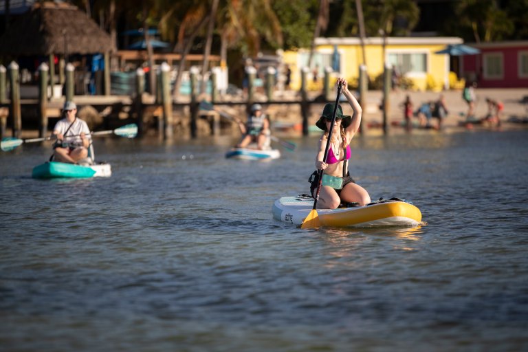 PopSci writer Amanda Reed kneeling on a BOTE Wulf SUP in the Florida Keys