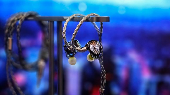 Shiny FiiO FA19 earphones hanging on a headphone stand