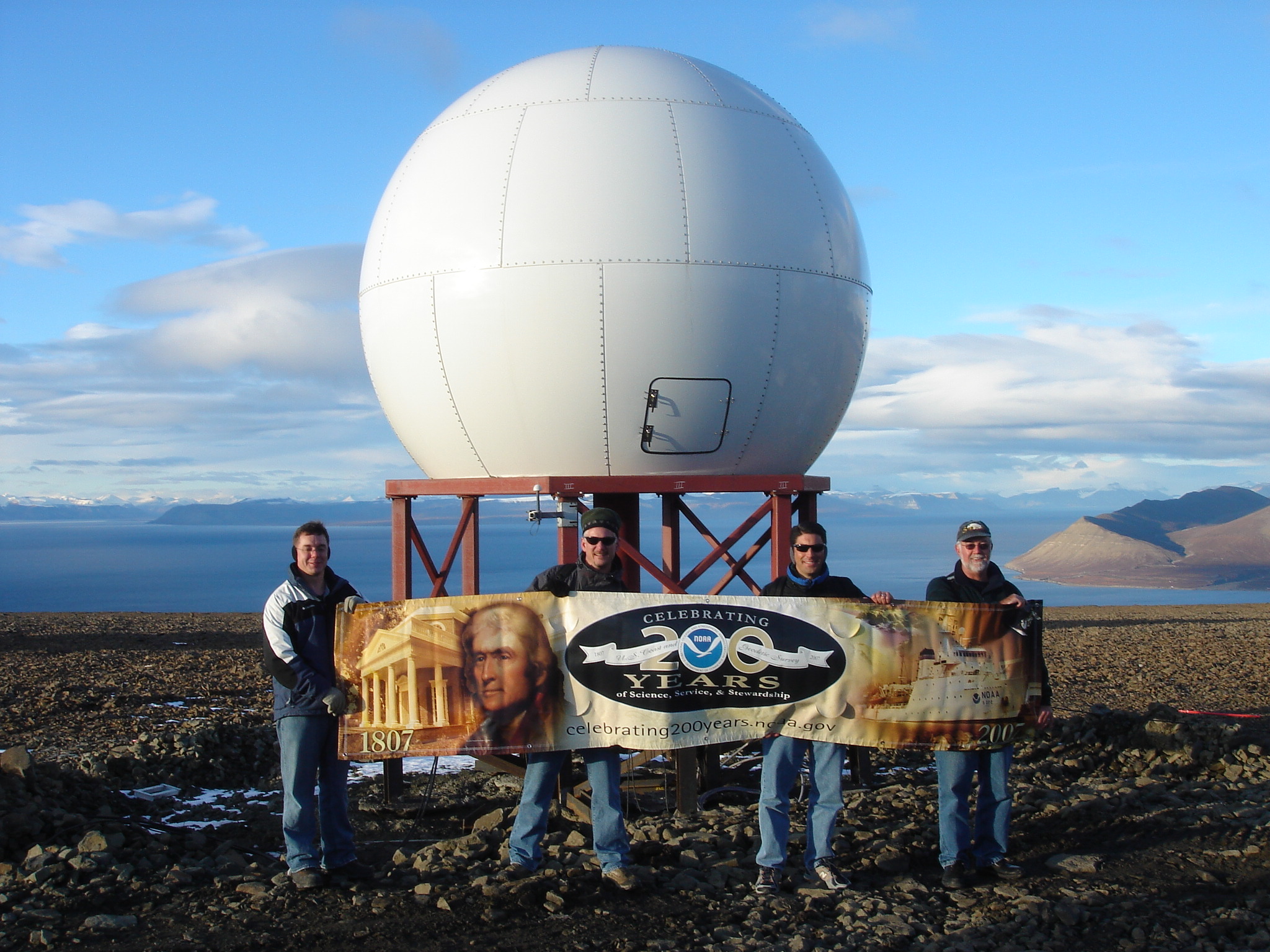 a group of people holding a sign stand in front of round satellite