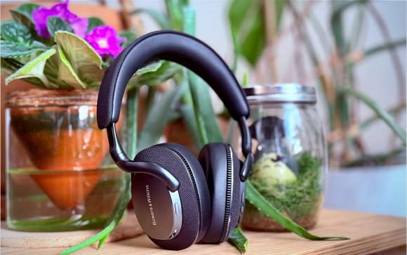 Black Bowers & Wilkins Px7 S3 headphones sitting in front of colorful flowers on a bamboo table