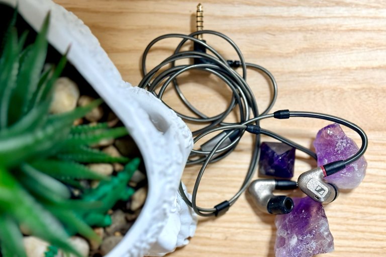 Metallic Sennheiser IE 600 shown draped on amethyst crystals on a blond wood surface