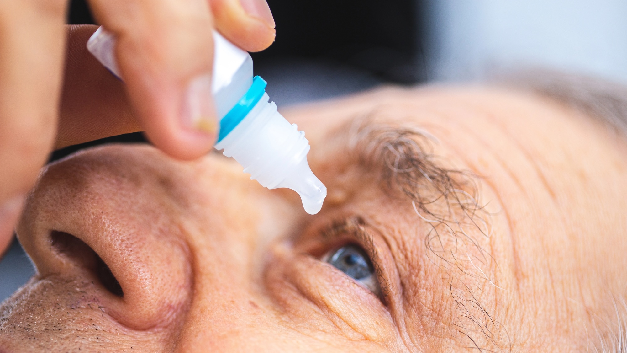 Close up of older man using eye drops