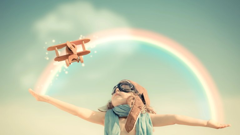 Happy kid playing with toy airplane against summer sky background