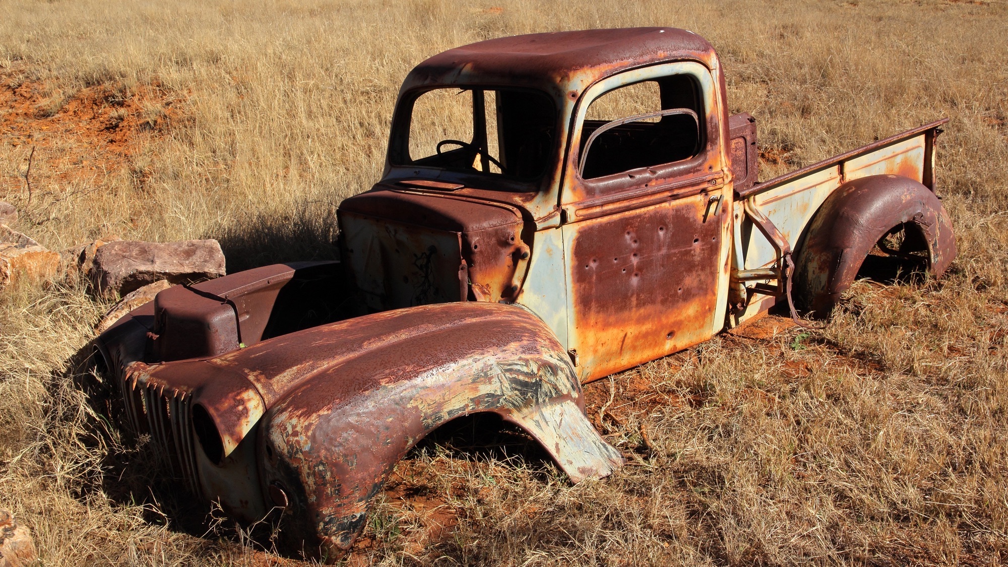 Wreck of a rusty old pickup truck out in the field