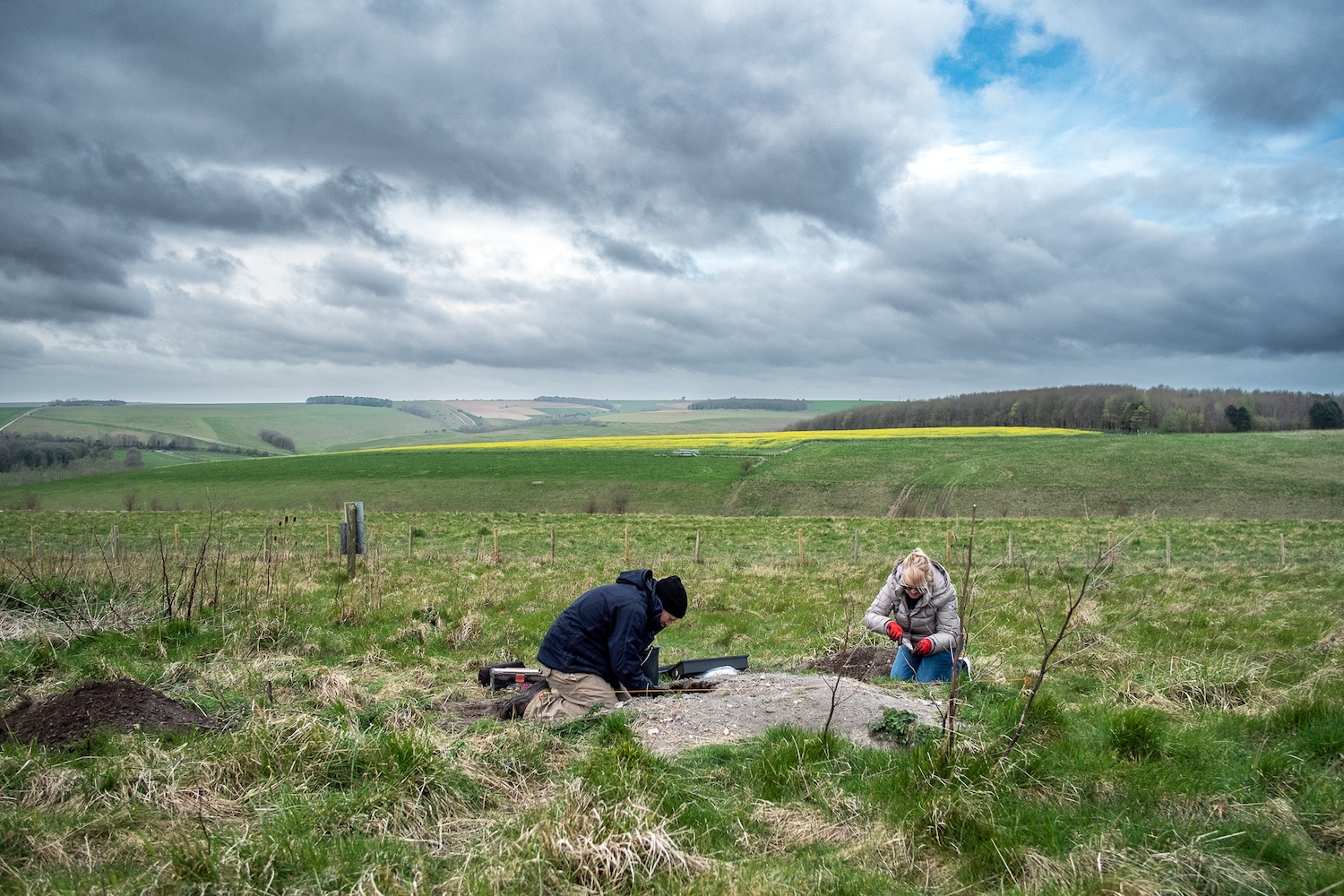 Two archaeologists working on a midden excavation in rural England on cloudy day