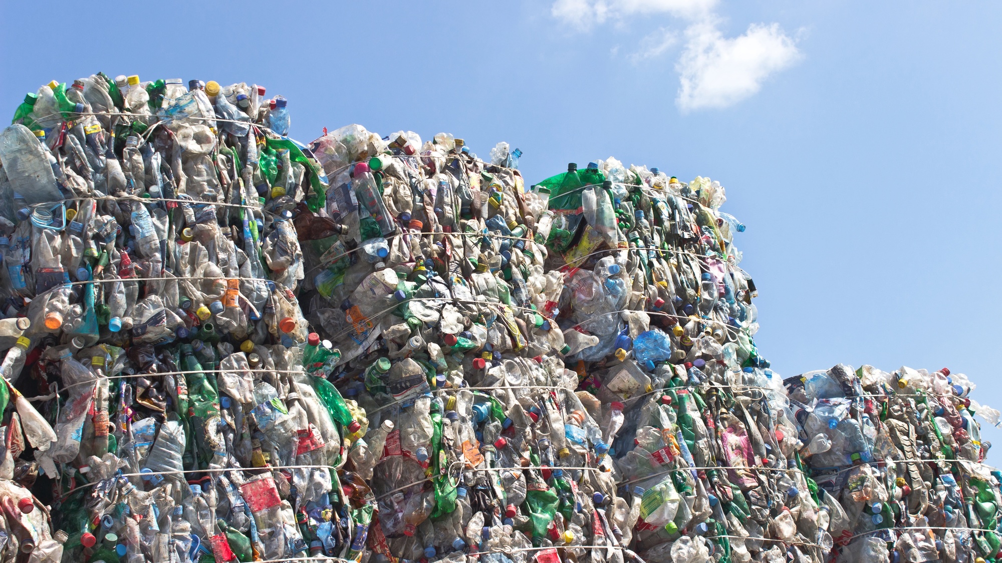 Stack of plastic bottles for recycling against blue sky