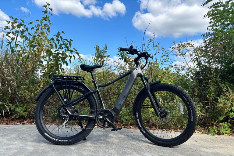 A grey Ride1Up Vorsa SUV ebike from the side against a green foliage background