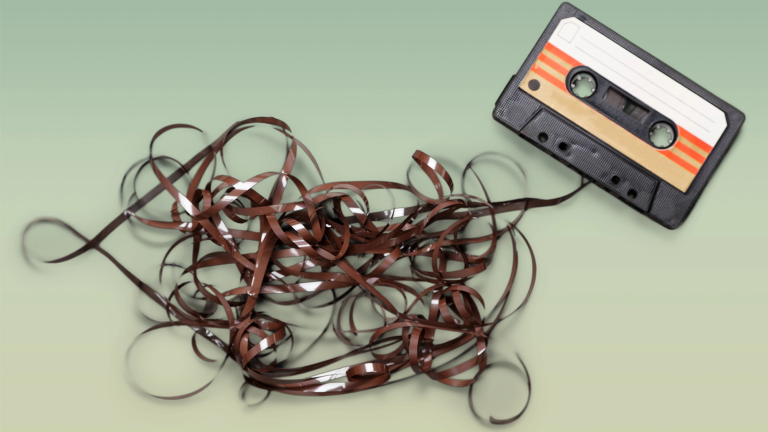 a rectangular cassette tape with lots of loose brown tape coming out