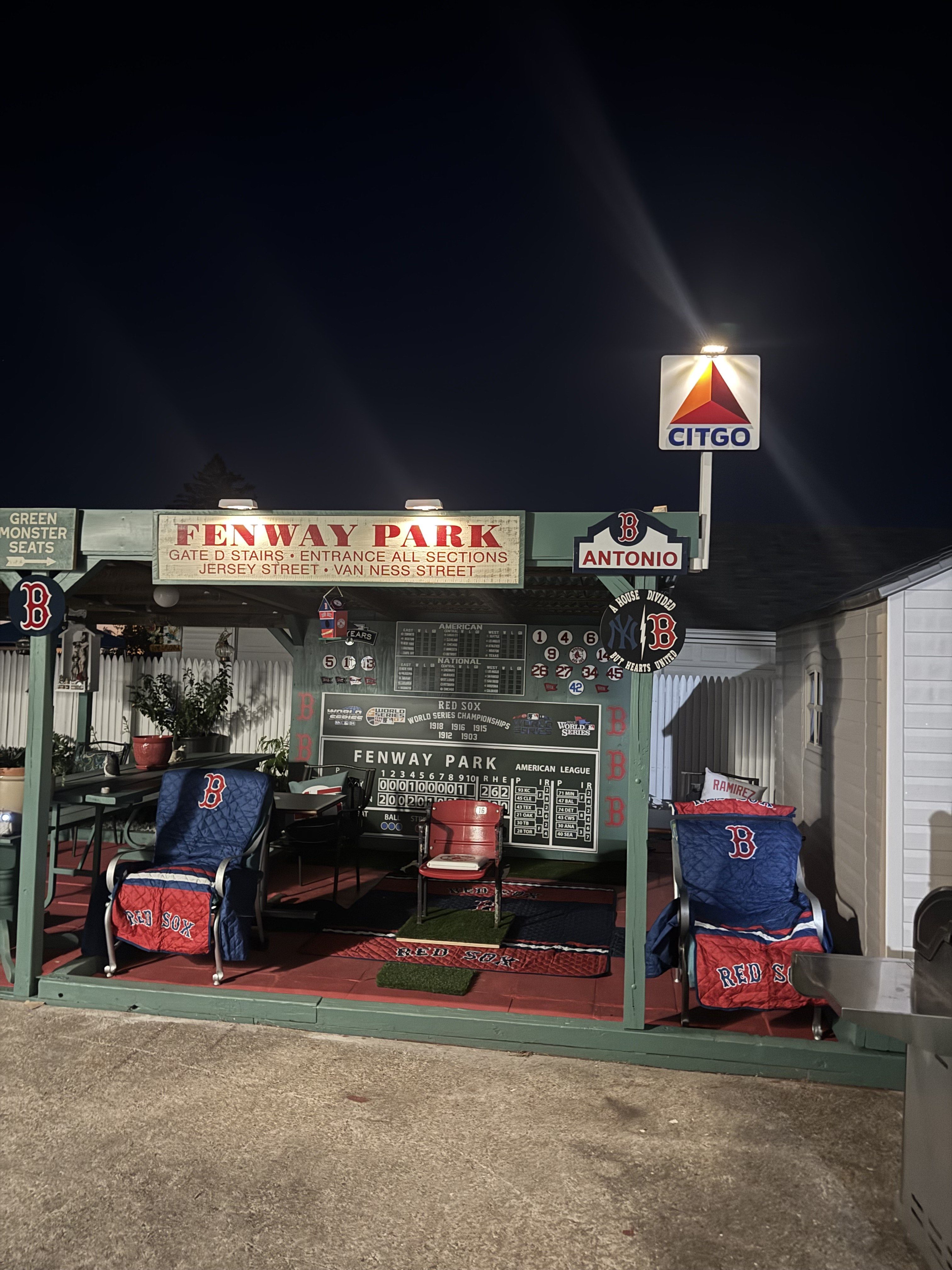 a backyard baseball park at night with lights on top of the roof