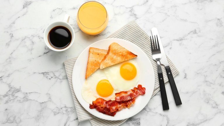 Delicious breakfast with sunny side up eggs served on white marble table, flat lay