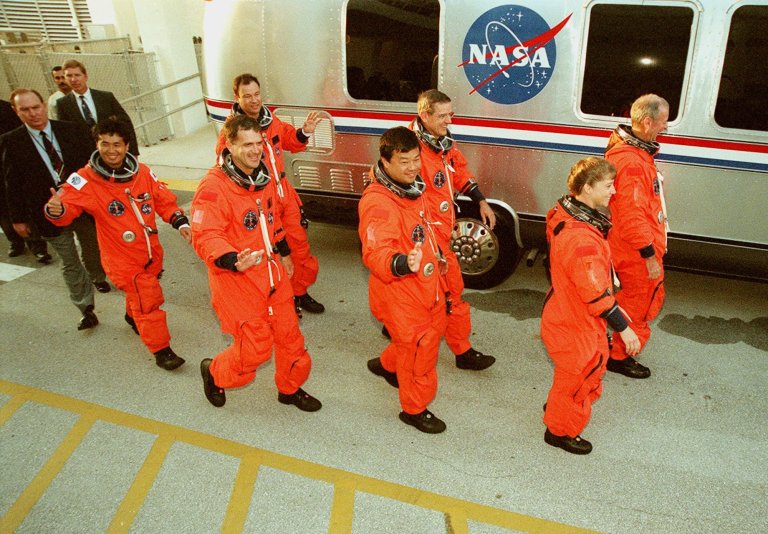 The STS-92 crew exits the Operations and Checkout Building on their way to the Astrovan and Launch Pad 39A for a simulated countdown. Walking left to right are (foreground) Mission Specialists Koichi Wakata of Japan, Peter J.K. “Jeff” Wisoff and Leroy Chiao; and Pilot Pamela Ann Melroy. Behind them are Mission Specialists Michael E. Lopez-Alegria and William S. McArthur Jr.; and Commander Brian Duffy. The crew is taking part in Terminal Countdown Demonstration Test activities that provide emergency egress training, opportunities to inspect the mission payload, and the simulated countdown. STS-92 is scheduled to launch Oct. 5 at 9:38 p.m. EDT on the fifth flight to the International Space Station. It will carry two elements of the Space Station, the Integrated Truss Structure Z1 and the third Pressurized Mating Adapter. The mission is also the 100th flight in the Shuttle program