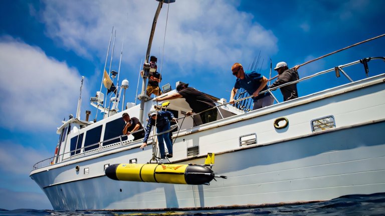 Research team lowering Redwing submersible into ocean from a boat