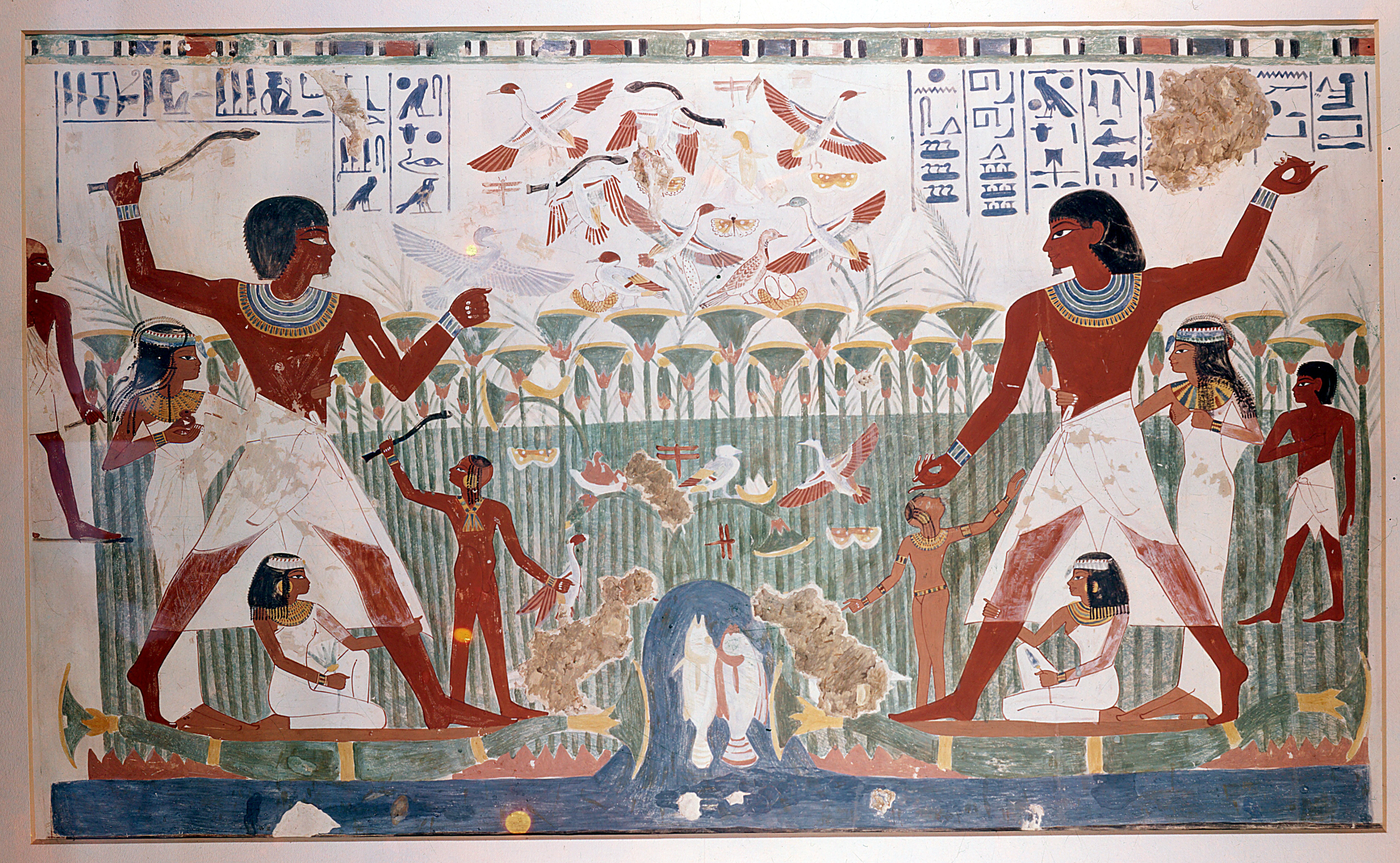 A vibrant ancient Egyptian tomb painting depicts a symmetrical scene of two male figures hunting birds in a marsh. The central figures are two large, dark-skinned men wearing white kilts and elaborate jewelry, each poised with a throw-stick. They are surrounded by smaller figures, including women and children. Above them, a flock of birds flies out of a dense papyrus thicket, with hieroglyphics bordering the top of the mural.