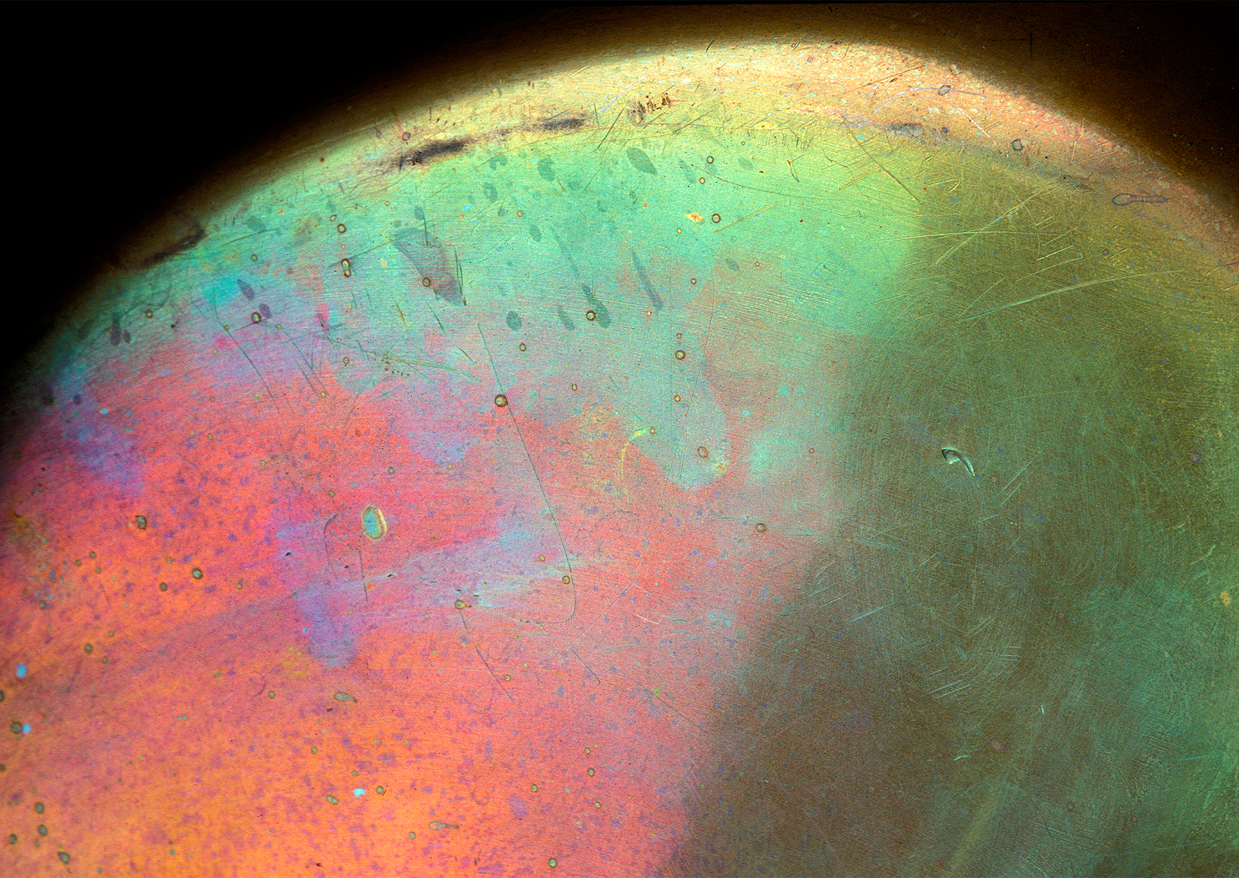 the bottom of a copper pt with red, orange, blue, and green tarnish