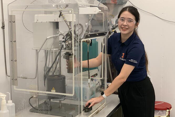 a scientist wearing protective eyewear and a university of illinois polo shirt works in a lab