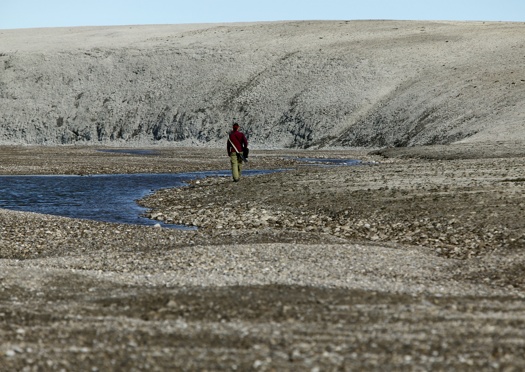 a woman in a red jacket walking in a crater