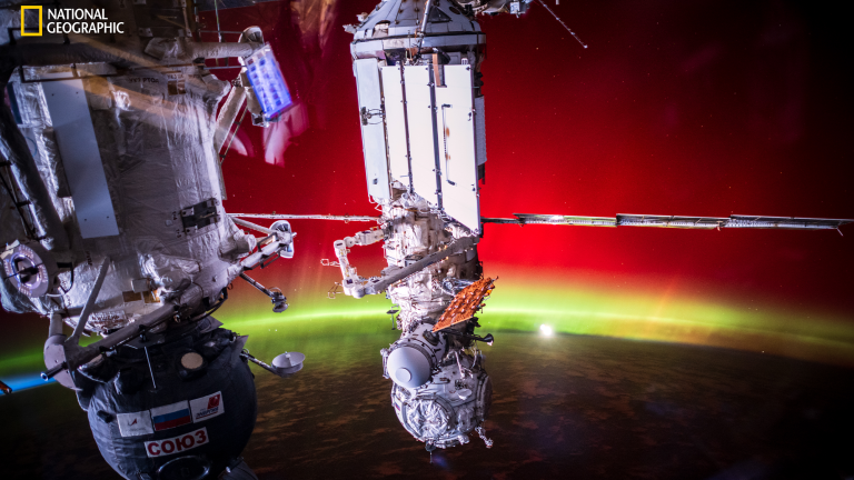 the international space station above the earth, with a green and red aurora shining on the planetImage: Photo by Don Pettit.