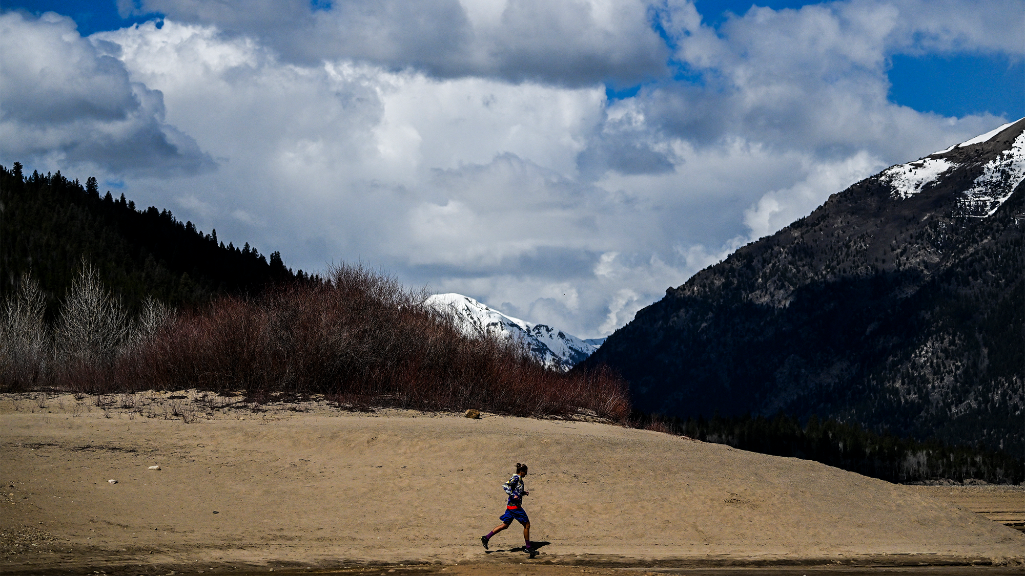 a woman running with snow-capped mountains in the background