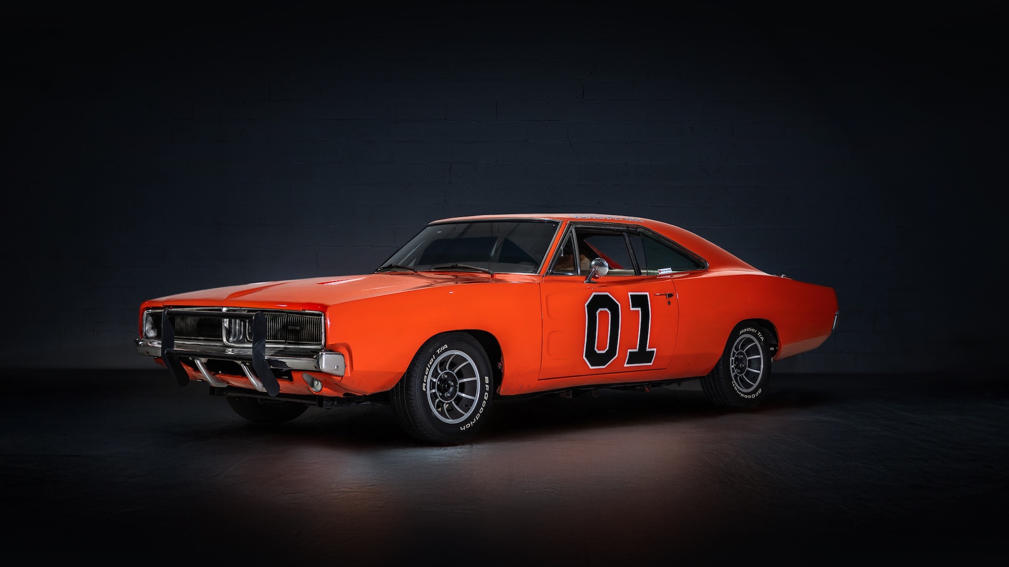 an orange car parked in a black room