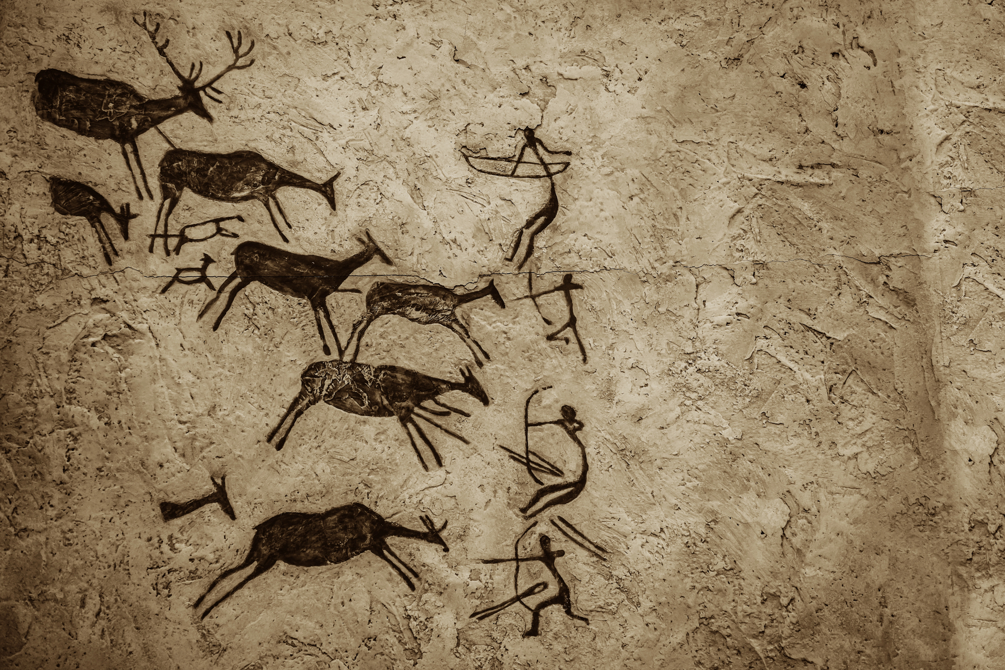 A textured photograph of a rock wall displays ancient cave paintings (rock art) in shades of sepia and brown. The paintings primarily depict scenes of human figures hunting stylized animals, including deer or elk, using bows, arrows, and spears.