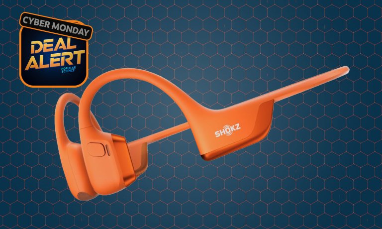 Orange Shokz OpenRun 2 bone-conduction headphones on a dark blue Amazon Cyber Monday background