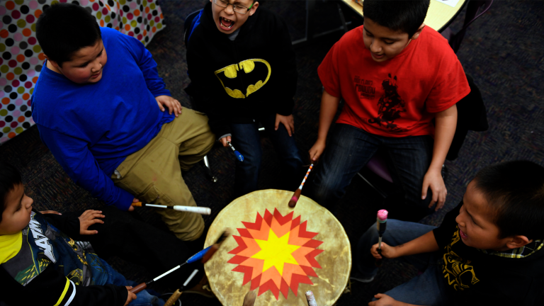 several boys sit around a tribal drum