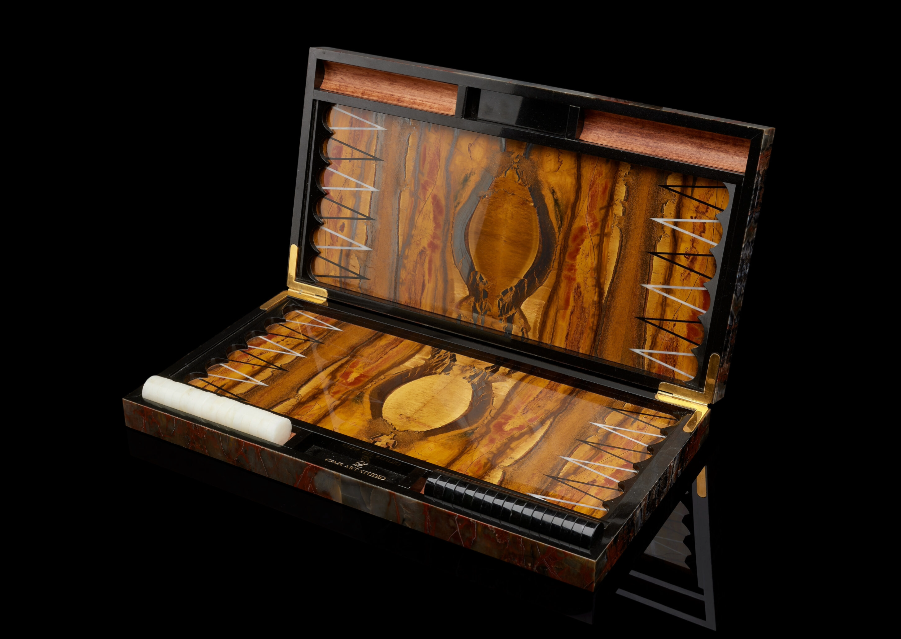 A backgammon set with board and pieces, also uncovered from Australia. The game is made with highly polished slabs of petrified wood from Arizona and has an interior of Australian tiger’s-eye. Game pieces are made of black and white nephrite. I