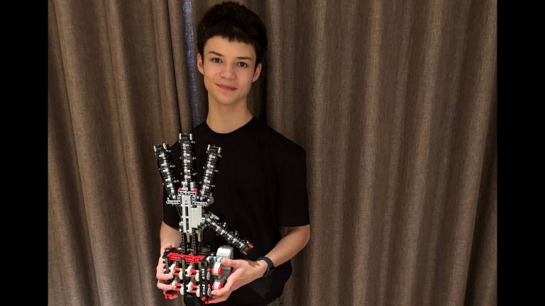 a teenage boy holds a robotic hand made out of legosUniversity of Bristol/Jared Lepora