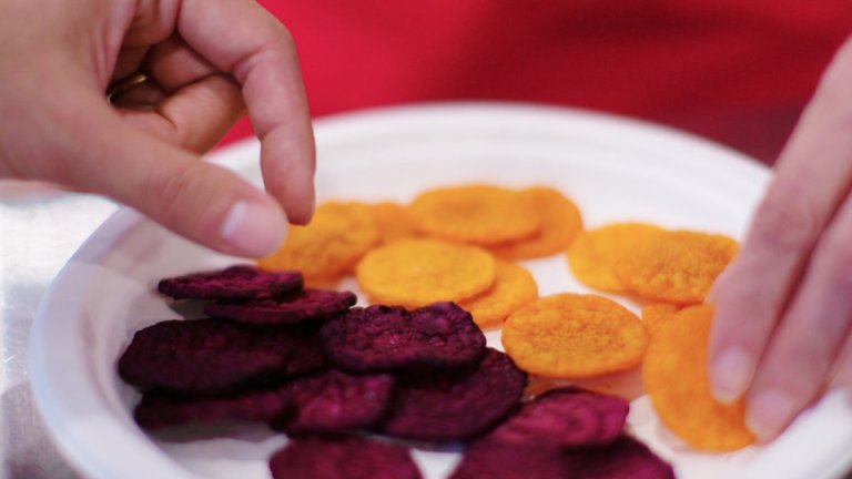 Close up of microwave vacuum dried beet chips and hands reaching to grab them
