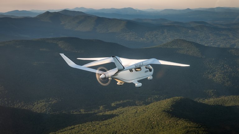 Electric plane flying over green mountains