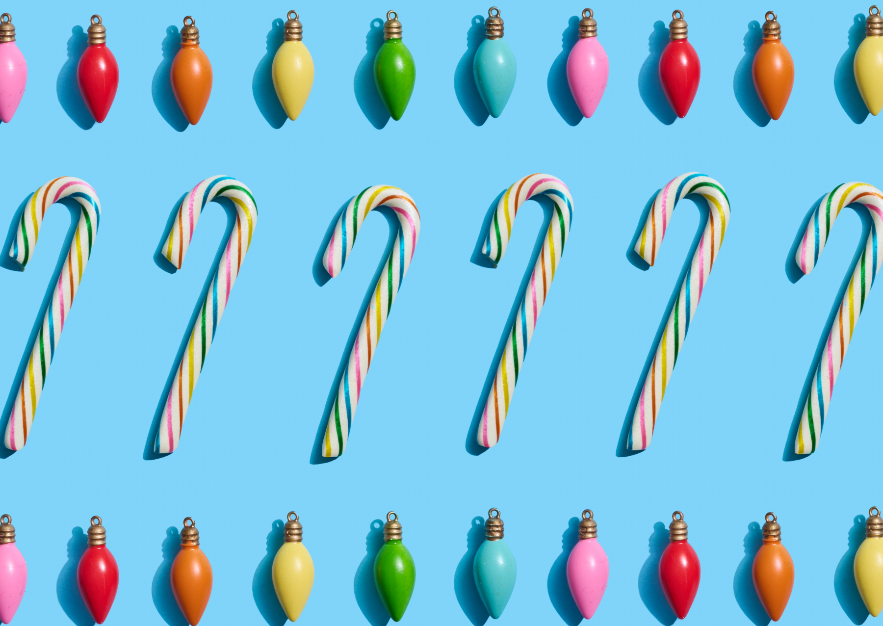 white candy canes with pink, red, yellow, green, and blue stripes in a line on a blue background with large christmas light bulbs of the same color