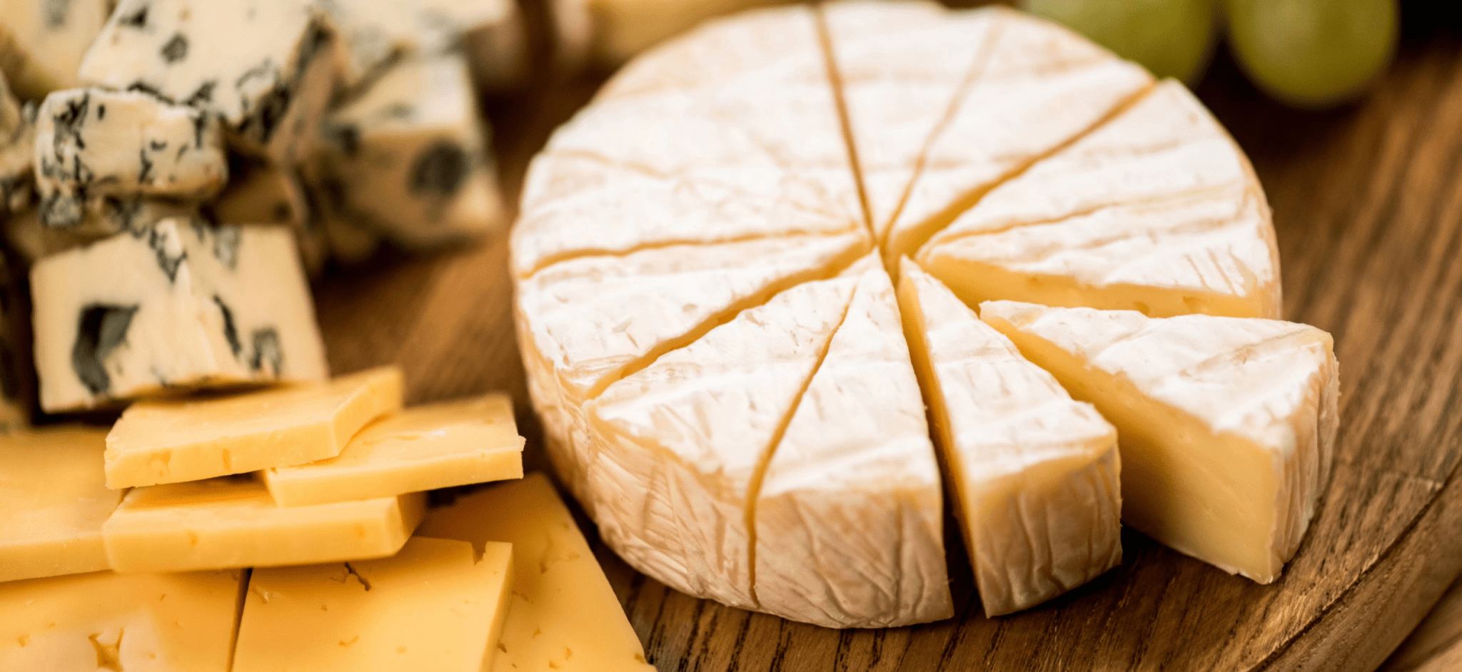 several cheeses on a wooden board
