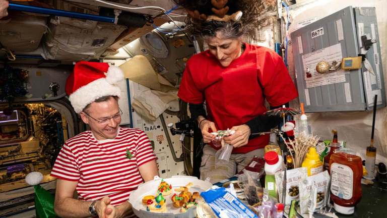 two astronauts share a holiday meal on the ISS