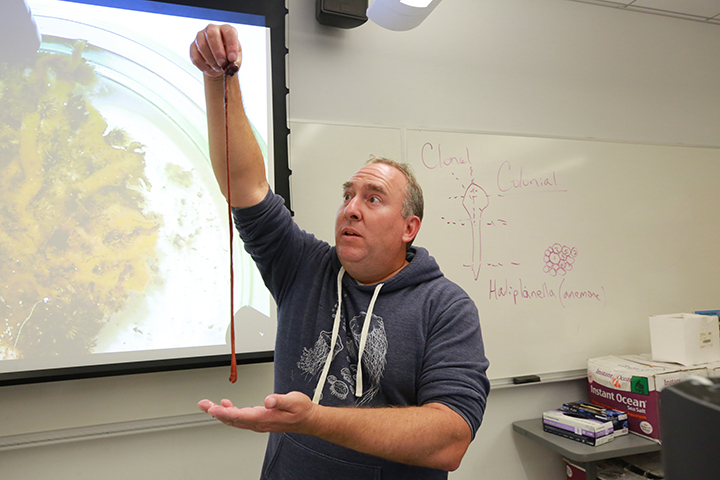 man holds up worm in classroom
