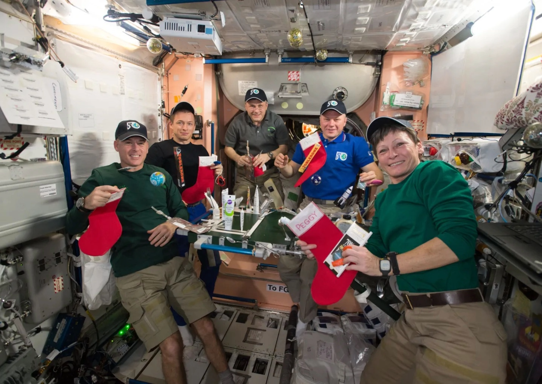 5 astronauts pose with christmas stockings