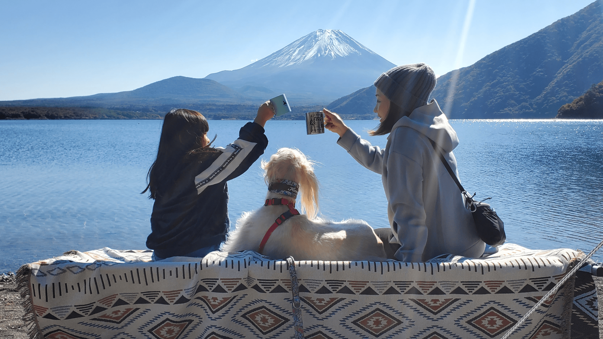 a mom and daughter camping with their dog. a tall mountain is in the foreground