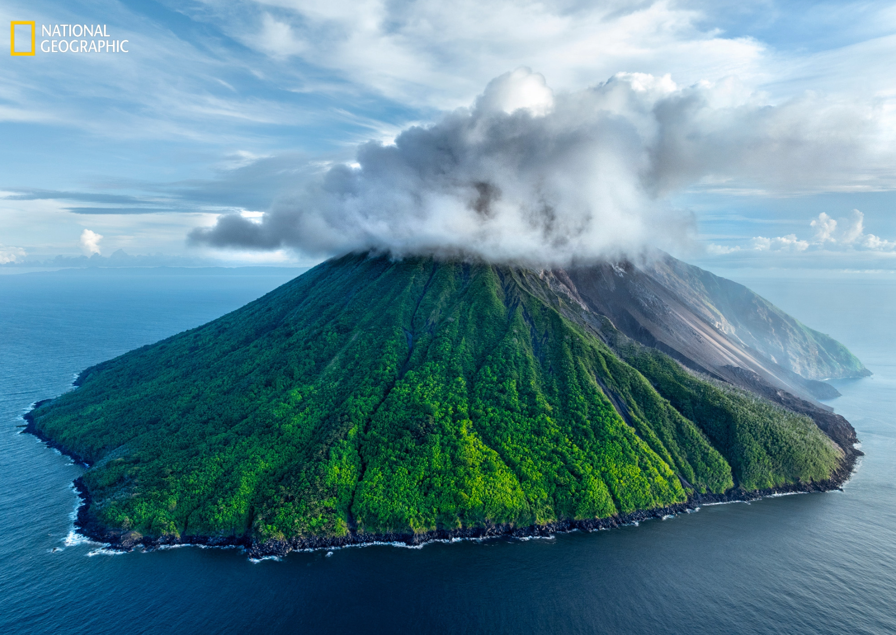 a large green island arises from blue ocean