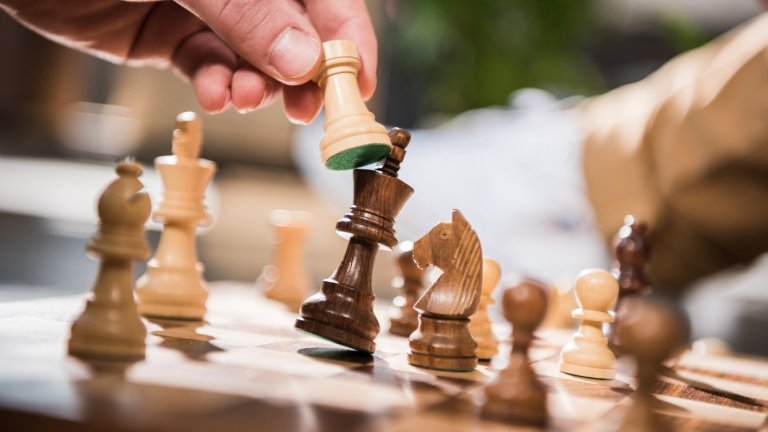 Close up of hands playing chess, with white checkmating