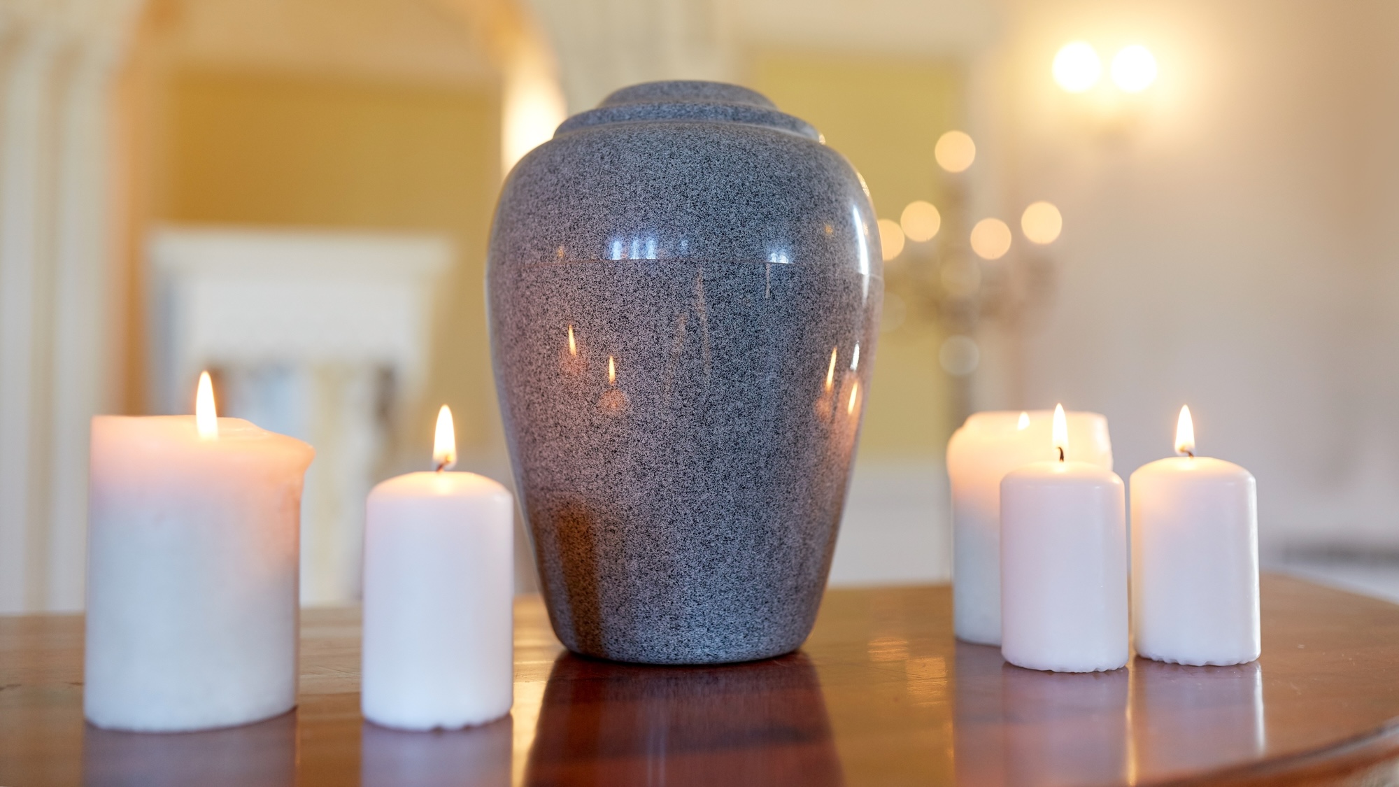 Funeral urn on table next to four lit candles
