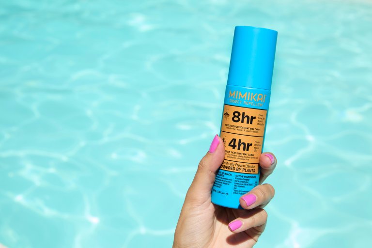 bug spray held by woman's hand over water