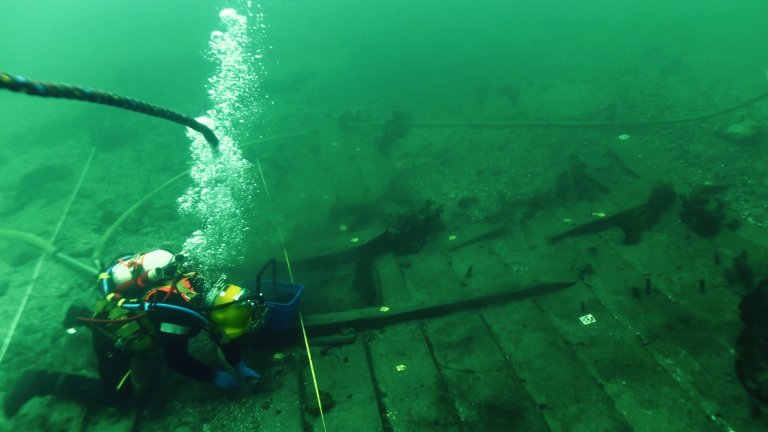 Diver underwater investigating Viking shipwreck