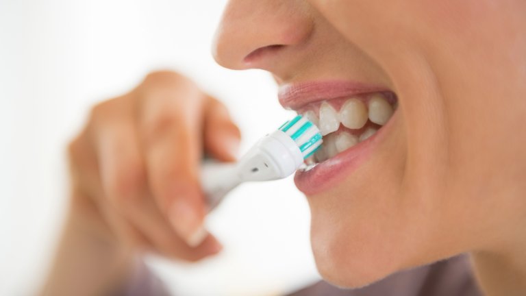Close up of woman brushing teeth using electric toothbrush