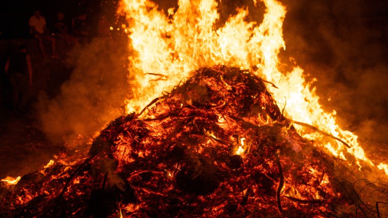 A photo of large bonfire in the night, glowing red with yellow flames.