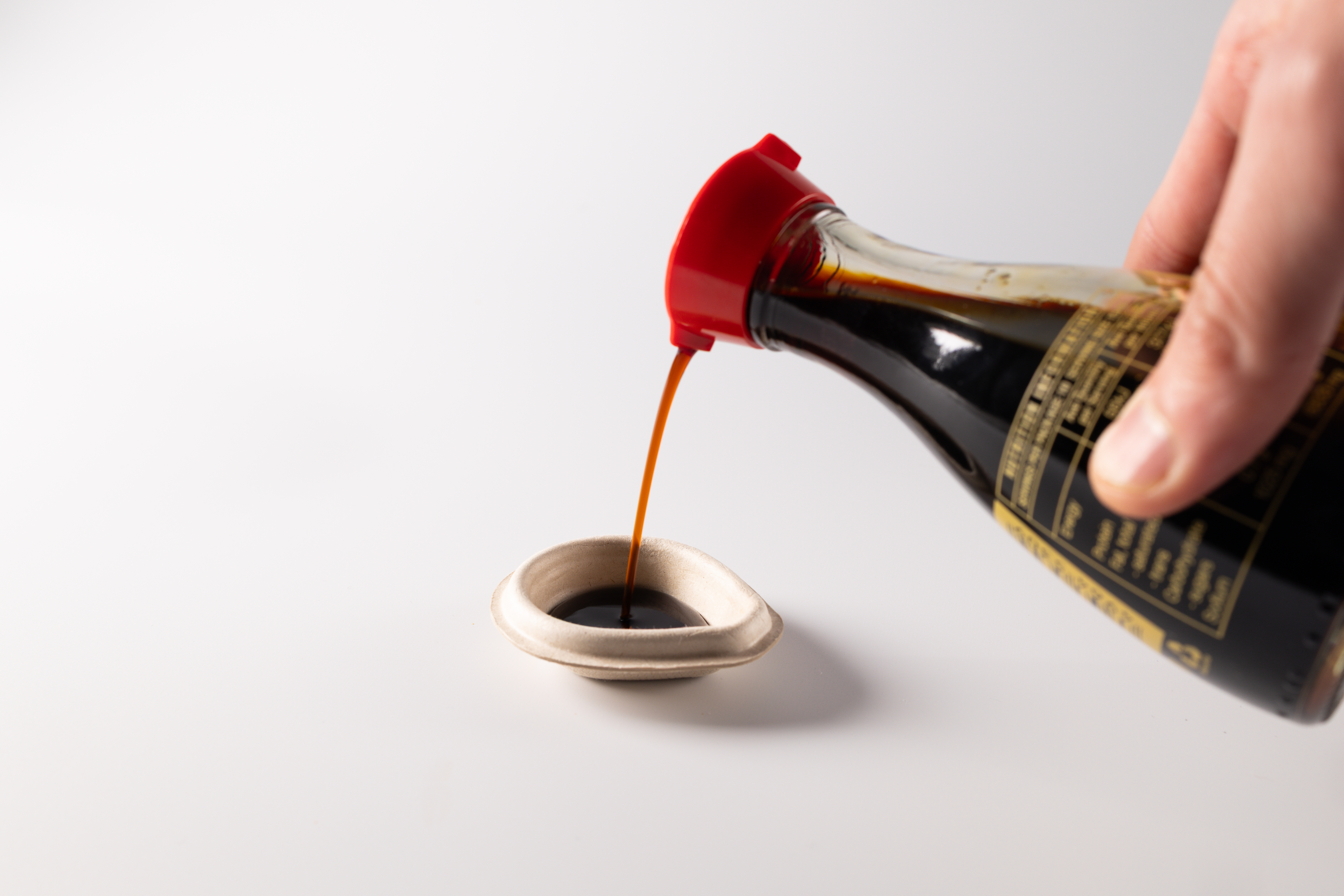 Plastic-free soy sauce container biodegrades in 4 weeks插图2 a hand pouring brown soy sauce into a container