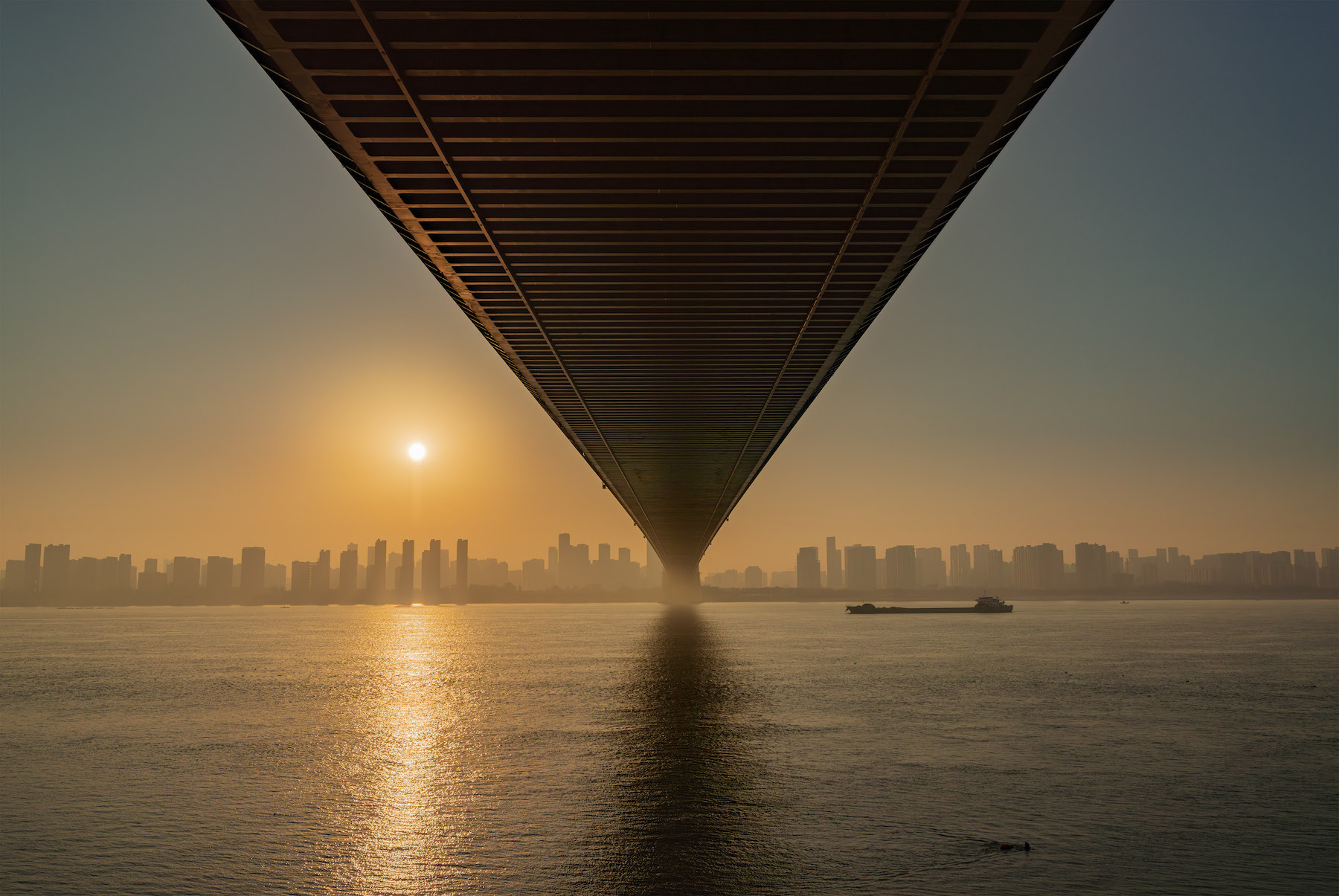 a barge passes under a bridge. city buildings in the background