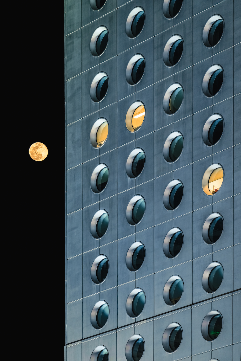 building with round windows, a full moon in the sky