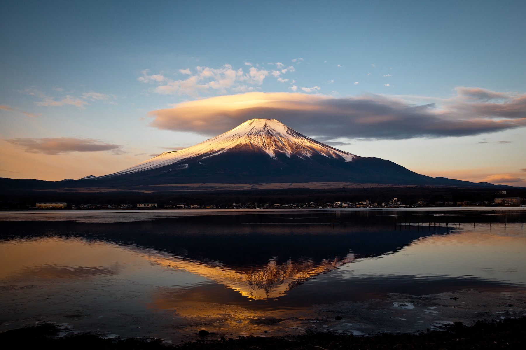 clouds over a mountain. a lake in the foreground