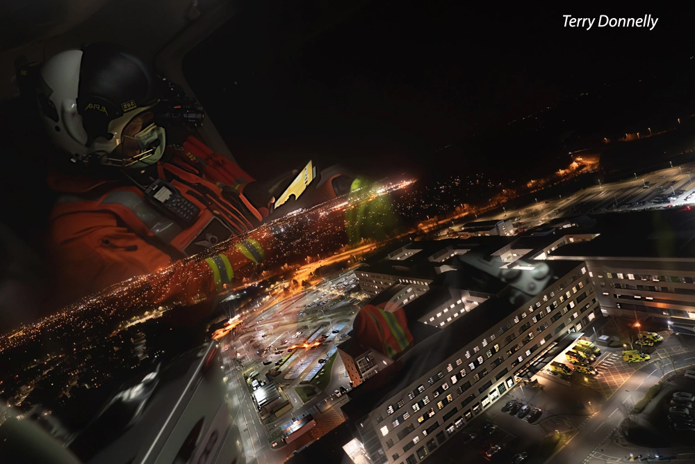 the refelction of an emergency worker in a helicopter over a hospital