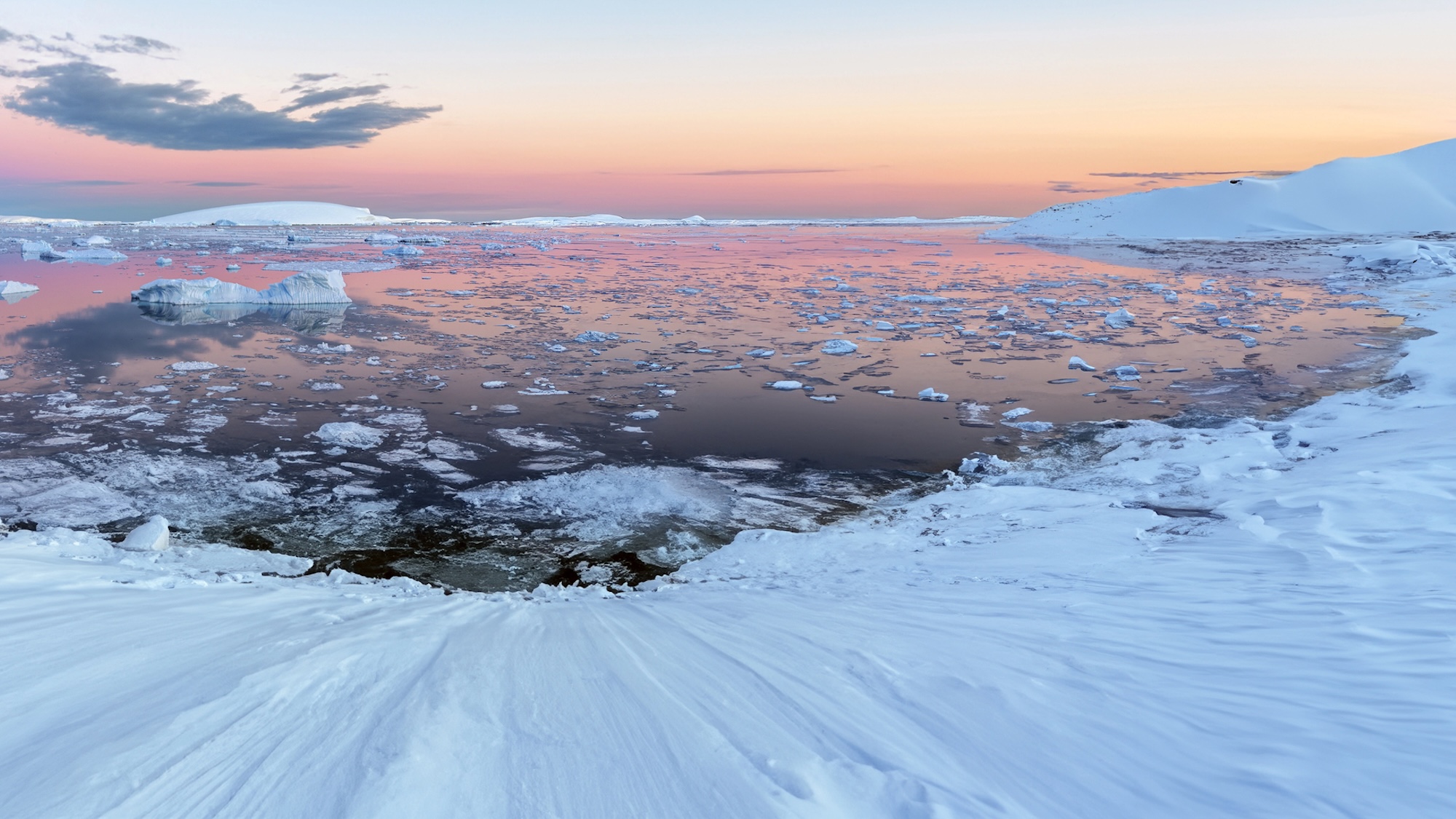 The Midnight sun over the icebergs in the Weddell Sea from the Antarctic Peninsula in Antarctica.